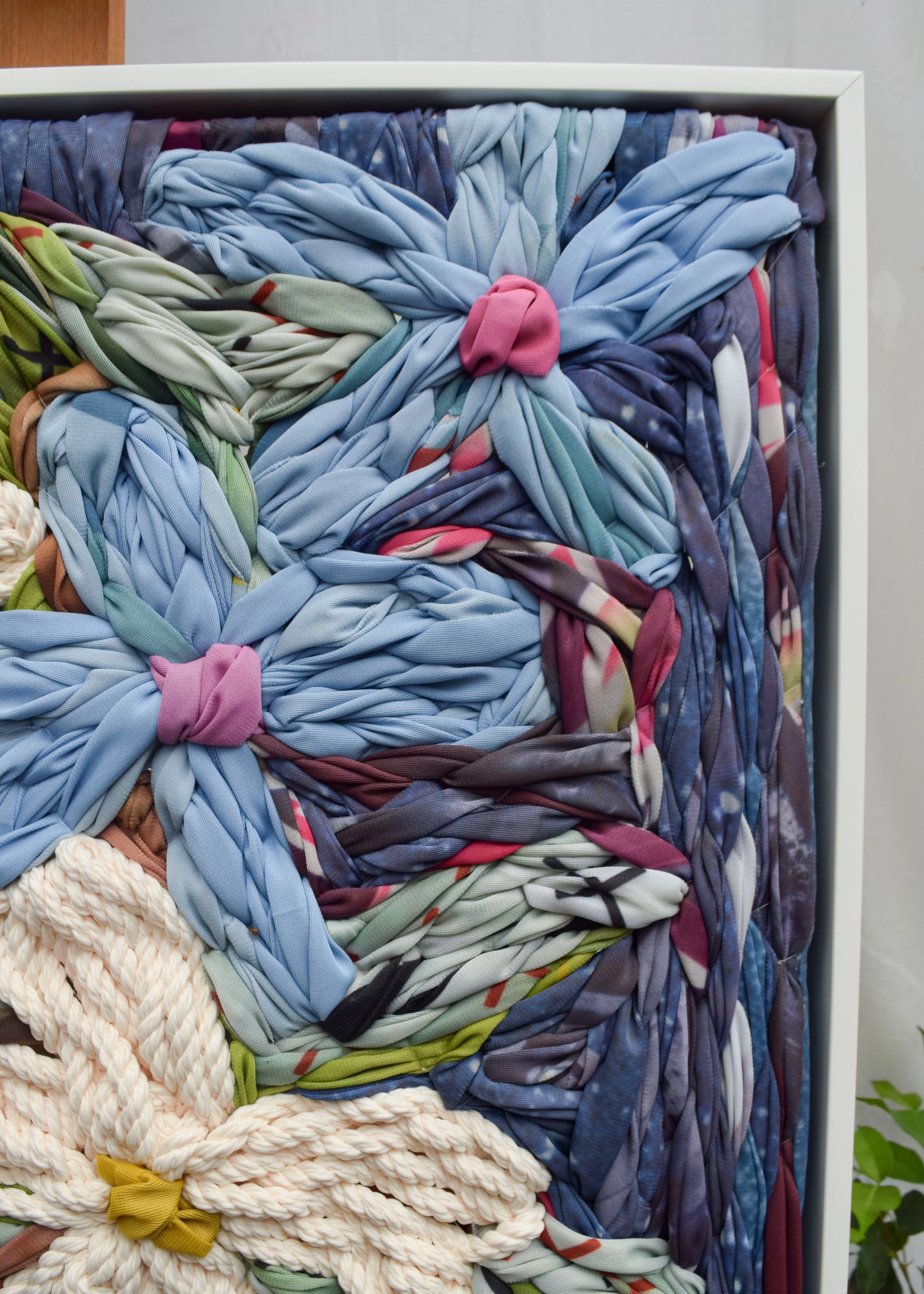 Close up detail of the texture in the botanical embroidery wall hanging depicting pale blue flowers